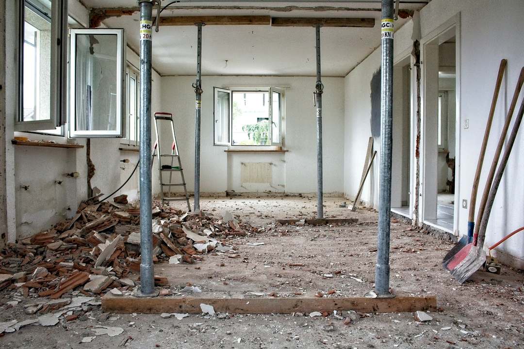 Woonkamer tijdens een verbouwing, met stalen stempels die het plafond ondersteunen